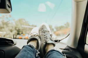 Someone sitting in a car on the passenger seat and putting her legs one the cockpit 